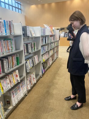 図書館で書棚の表示を見るためにレティッサオンハンドを使っている女性 図書館で書棚の表示を見るためにレティッサオンハンドを使っている女性